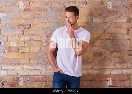 Porträt eines Denkens hübscher junger Mann in einem weißen T-Shirt. Stockfoto