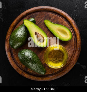 In Scheiben geschnitten und ganze Avocados und Öl Stockfoto