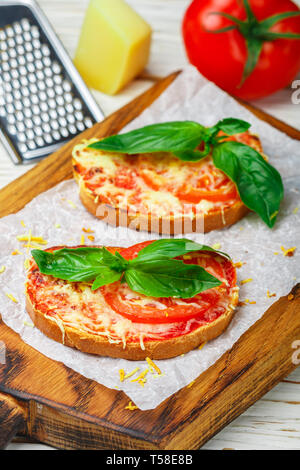 Gebackenes Brot Toast mit Käse, Tomaten und Basilikum. Mini Pizza. Feinkost Sandwich für Gourmets. Selektiver Fokus Stockfoto