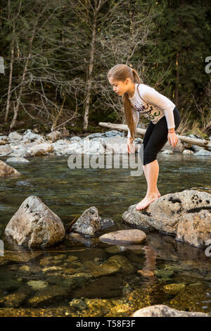 Olallie State Park, in der Nähe von North Bend, Washington, USA. Neun Jahre altes Mädchen zögern und denken sie zweimal vor dem hüpfen auf den nächsten Felsen im Norden f Stockfoto