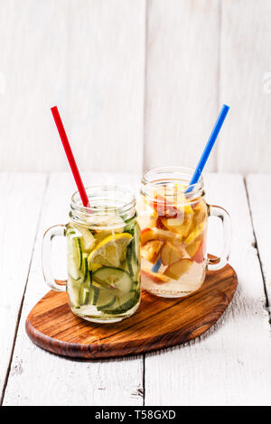 Zwei Becher infundiert Detox-diät erfrischenden Wassern - zuerst mit Gurke und Zitrone, zweite mit Zitrone und Pfirsich Stockfoto