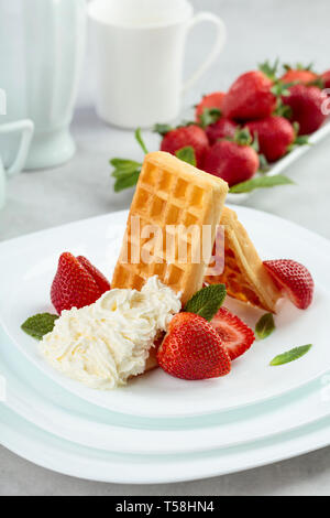 Waffeln mit Erdbeeren und Sahne garniert mit frischer Minze. Stockfoto