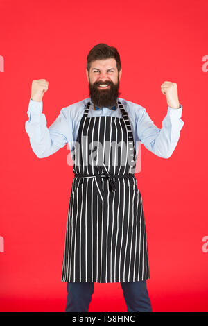 Im ein Sieger. Bärtiger Mann feiern Sieg oder Erfolg. Brutaler Mann im eleganten Schürze mit glücklich gewinnen Geste. Cook Mann mit eleganten Arbeit einheitlich. Glücklicher Mann mit langen hipster Bart. Stockfoto