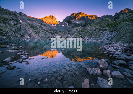 Sunrise leuchtenden Gipfeln und Reflektieren im kristallklaren See Höhe Stockfoto