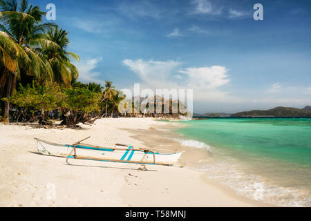 Tropische Malcapuya mit traditionellen Philippinen Insel Bangka Boot mit azurblauem Wasser und weißen Sandstrand. Reisen Urlaub auf den Philippinen. Stockfoto