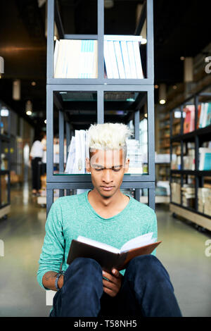 Neugierig schwarzen Studenten lesen Buch in der Bibliothek Stockfoto