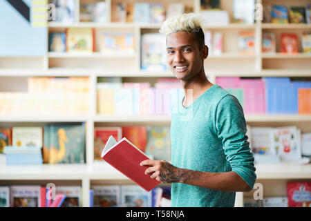 Hübscher junger Student in der Bibliothek Stockfoto