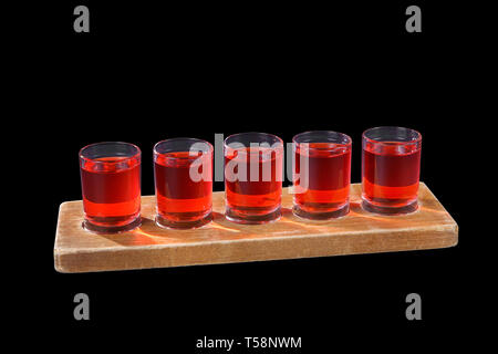 Rot, Farbe transparent Cocktails, eine Reihe von Aufnahmen in einer Zeile, fünfmal auf einem Stand aus Holz, Substrat, Seitenansicht, Isolierte schwarze Hintergrund, Dr Stockfoto