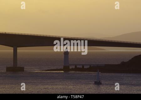 Boot Segeln bei Sonnenuntergang towarsds die Skye Road Bridge und Kyleakin Leuchtturm. Schottland, Großbritannien. Stockfoto