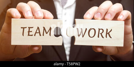 Geschäftsmann sammelt Puzzles aus Holz mit dem Wort Teamwork. Gemeinsame Erreichung eines gemeinsamen Ziels. Hohe Effizienz und Leistung. Business Kommunikatio Stockfoto