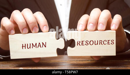 Geschäftsmann sammelt Puzzles aus Holz mit dem Wort Human Resources. Recruitment, HR, Führung und Teambuilding. Wirtschaft und Technologie Konzept. Mana Stockfoto