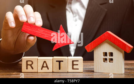 Unternehmer halten Sie die Nach-unten-Pfeil auf Holzklötze mit dem Wort- und Haus. Geringes Interesse an Hypotheken. Die Zinsen für die Hypothek. Stockfoto