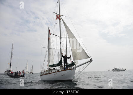 Sir Robin Knox-Johnson an Bord Suhali, wird durch eine Flotte von Schiffen eskortiert, wie es kommt, der die Ziellinie seiner ursprünglichen Reise in Falmouth zu überqueren, zum 50. Jahrestag seiner Fertigstellung des ersten solo Non-stop-Weltumrundung. Stockfoto
