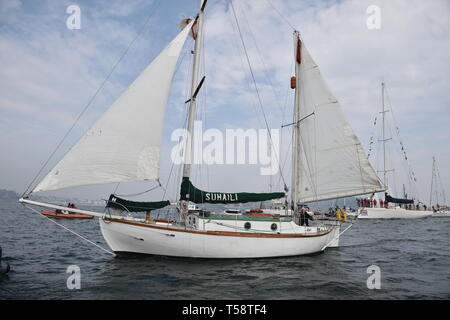 Sir Robin Knox-Johnson an Bord Suhali, wird durch eine Flotte von Schiffen über die Ziellinie seiner ursprünglichen Reise in Falmouth begleitet, zum 50. Jahrestag seiner Fertigstellung des ersten solo Non-stop-Weltumrundung. Stockfoto