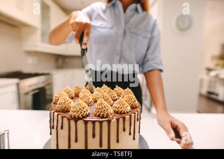 Frau Koch schneiden einen Kuchen, beim Kochen in der Küche zu Hause. In der Nähe der Partei chef Schneiden frisch gebackenen Kuchen mit Messer. Stockfoto