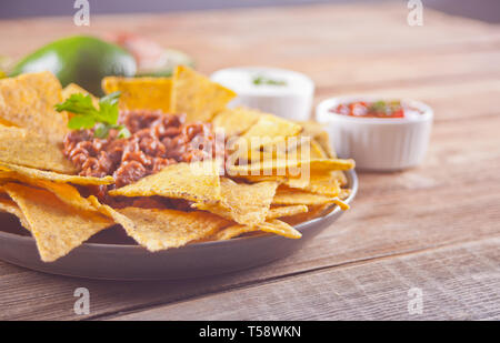 Nachos mit Salsa und Sour Cream Dips auf dem hölzernen Tisch Stockfoto