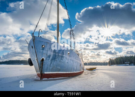 Alte und kaputte verlassenes Schiff auf Eis am sonnigen Wintertag in Küste Finnland. Stockfoto