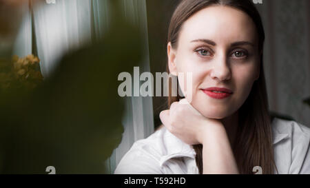 Portrait von attraktiven brünette Frau. Home Portrait einer Frau mit roten Lippen in einem weißen Hemd Stockfoto