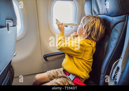 Kleinen Jungen spielen mit Spielzeug Flugzeug im kommerziellen jet Flugzeug fliegen im Urlaub Stockfoto