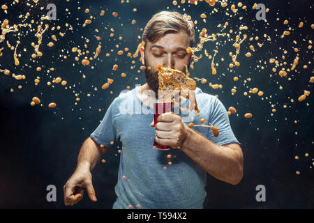 Mann trinkt ein Cola im Studio. Junge lächelnde glücklich kaukasischen Kerl Öffnung kann mit Cola und genießen die Spray. Werbung Bild über Lieblingsgetränk. Lifestyle und menschlichen Emotionen Konzept. Stockfoto