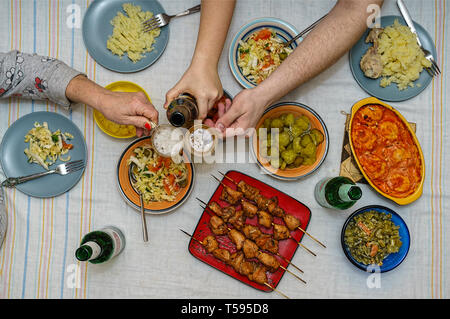 Toast und Beats mit Brille im Rahmen einer festlichen Familie fest. Flach Tisch mit Beilage von Kartoffeln, gebackene Hackfleischbällchen, Fleischspieße, Kebabs und Stockfoto