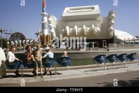 Eine Familie stellt, an einem sonnigen Tag, während auf einer Sitzreihe vor der Chrysler Pavillon, 1964 in New York World's Fair, Flushing Meadows Park, Queens, New York, Mai, 1964 ausruhen. () Stockfoto