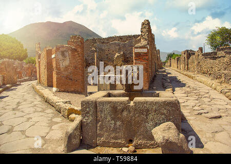 Alte Brunnen in Pompeji auf den Vesuv im Hintergrund, Kampanien, Italien. Römische Straßen Stockfoto