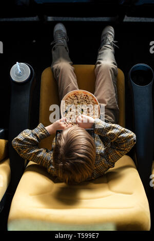 Ansicht von oben der Boy essen Popcorn im Kino Stuhl in der Nähe von Papier Schale Stockfoto