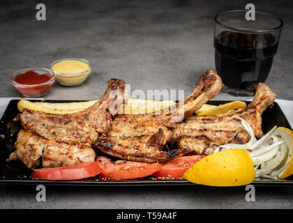 Lecker gegrilltes Schweinefleisch Steak serviert mit Bratkartoffeln, frischen Tomaten, Zwiebeln und Zitronen Stockfoto