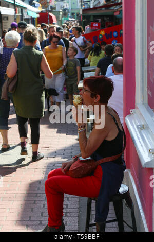 Frau essen Eis sitzen auf der Straße. Brighton Stockfoto