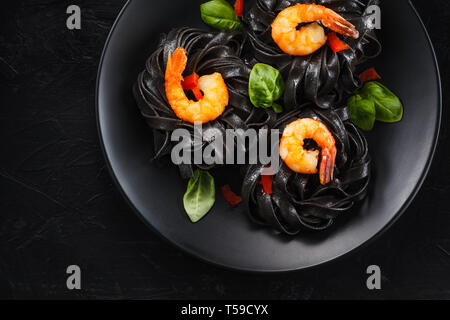 Squid inked Tagliatelle mit Garnelen auf schwarzen Hintergrund. Stockfoto