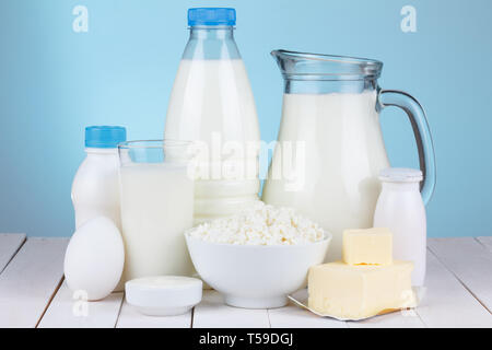 Natürliche organische Molkereiprodukte, Milch, Quark, Eier, Butter, Joghurt, Butter und saure Sahne auf weißem Holz- Ballen und blauem Hintergrund noch Leben Stockfoto