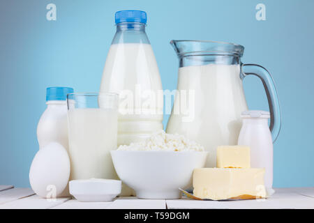 Natürliche organische Molkereiprodukte, Milch, Quark, Eier, Butter, Joghurt, Butter und saure Sahne auf weißem Holz- Ballen und blauem Hintergrund noch Leben Stockfoto