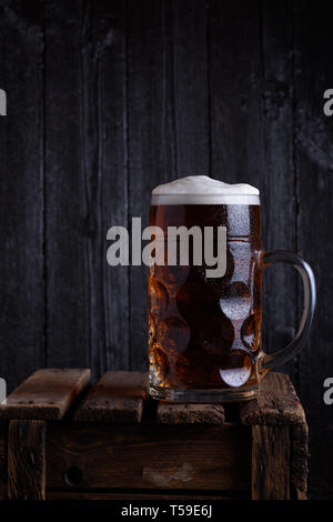 Riesige Bierkrug auf vintage Holzkiste mit dunklen Hintergrund noch Leben Stockfoto