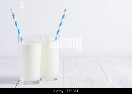 Zwei Gläser Milch mit blauen abgestreift Papier Trinkhalme auf hölzernen Tisch noch Leben Stockfoto