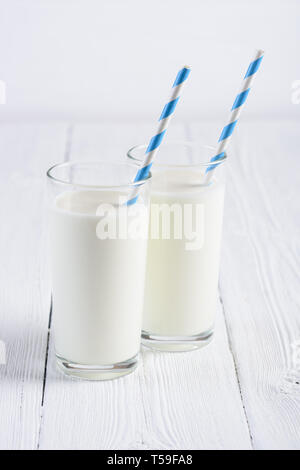 Zwei Gläser Milch mit blauen abgestreift Papier Stroh auf weiße Holztisch still life Stockfoto