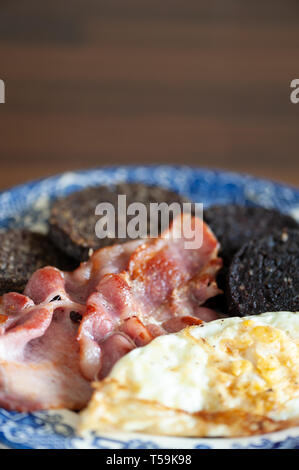 Warmes Frühstück mit Speck, Spiegelei, Blutwurst in Scheiben geschnitten und Haggis. Stockfoto