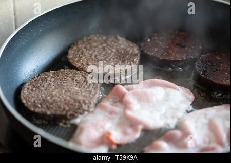 Sizzling Speck in einer Pfanne mit Blutwurst in Scheiben geschnitten und Haggis. Ein gebratenes Frühstück im Bilden. Stockfoto