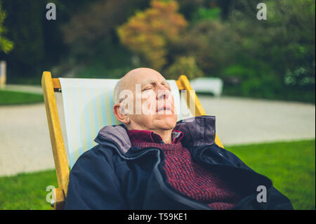 Ein älterer Mann entspannt im Liegestuhl im Freien Stockfoto