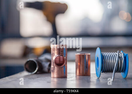 Closeup Löten, Sanitär, Bau professionelle Werkzeuge, Teile von Kupferrohren auf einer hölzernen Hintergrund. Konzept der professionellen Instandsetzung Wasser suppl. Stockfoto