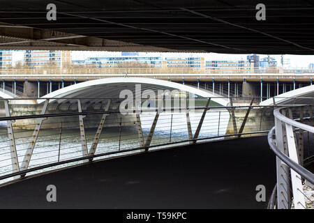 Unter der Chelsea Bridge. Blick auf die Themse und die Eisenbahnbrücke. Fußgängerbrücke an der Battersea Park. Stockfoto