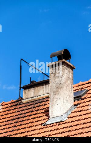Alte Kamin auf dem roten Dach. Alte Dach. Ökologische Heizung im Haus. Stockfoto