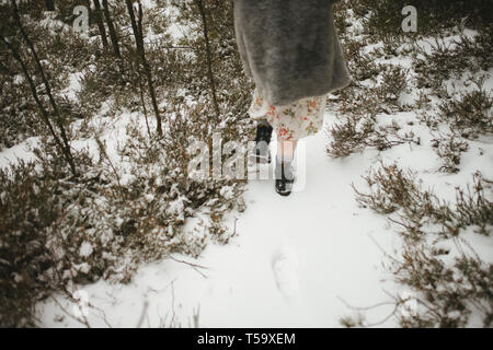 Beine von einem Mädchen, das durch den Wald im Winter Stockfoto