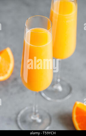 Brunch Mimosa klassische Cocktail aus Orangensaft und Sekt oder Champagner in Flöte Gläser auf einem grauen Tabelle gemacht. Stockfoto