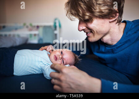 Ein junger Vater auf der Suche nach einem neugeborenen Baby zu Hause. Stockfoto