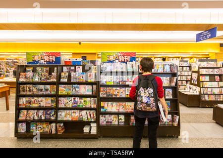 Ein hippie Kunden tragen Rucksack ist die neueste Version der beliebten Manga in den Regalen Kinokuniya, Singapur. Stockfoto