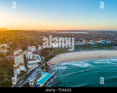 Bondi Beach Drone Schuß bei Sonnenuntergang mit Sydney CBD im Hintergrund bei Sonnenuntergang Stockfoto