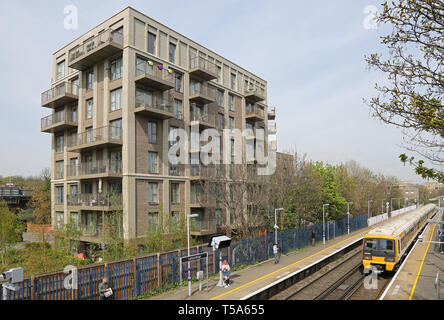 Ein Zug kommt an catford Bridge Station, London, UK. Neue Wohnung Block darüber hinaus - eine von vielen kürzlich in Catford gebaut. Stockfoto