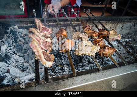 Auf dem Grill, eine Menge Fleisch gebraten am Spieß, der Koch dreht seine shish Kebabs. Hand eines Mannes, Pommes leckere Fleisch von Schwein am Spieß in Stockfoto