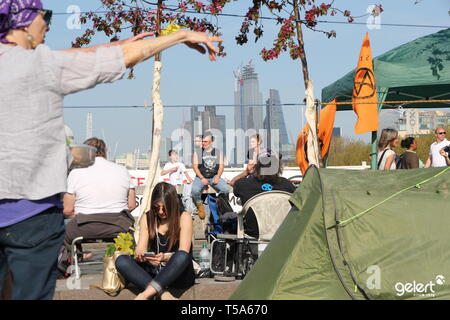 Junge aussterben Rebellion Demonstranten entspannen und plaudern über die Waterloo Bridge mit einem dramatischen kontrastierenden Kulisse der Stadt Wolkenkratzer und Zelte Stockfoto